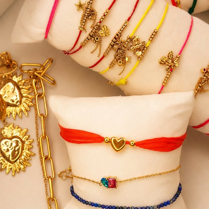 Bracelets et colliers dorés Peach Banana présentés sur des coussins beiges — cinq pépites au choix pour 35 euros